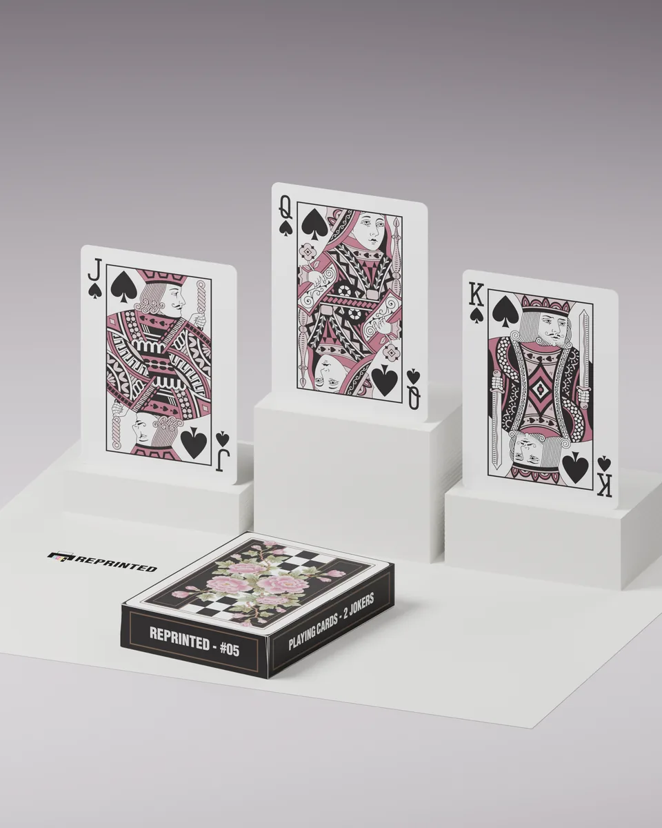 The jack, queen and king of spades from REPRINTED #05 standing on white blocks, the tuck case in front